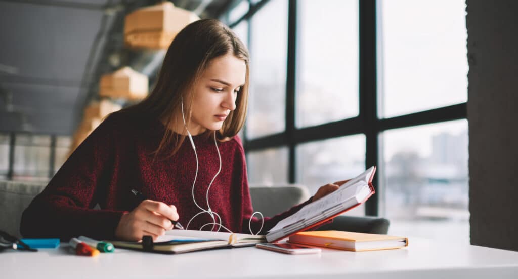 Older student studying notebooks and listening to music