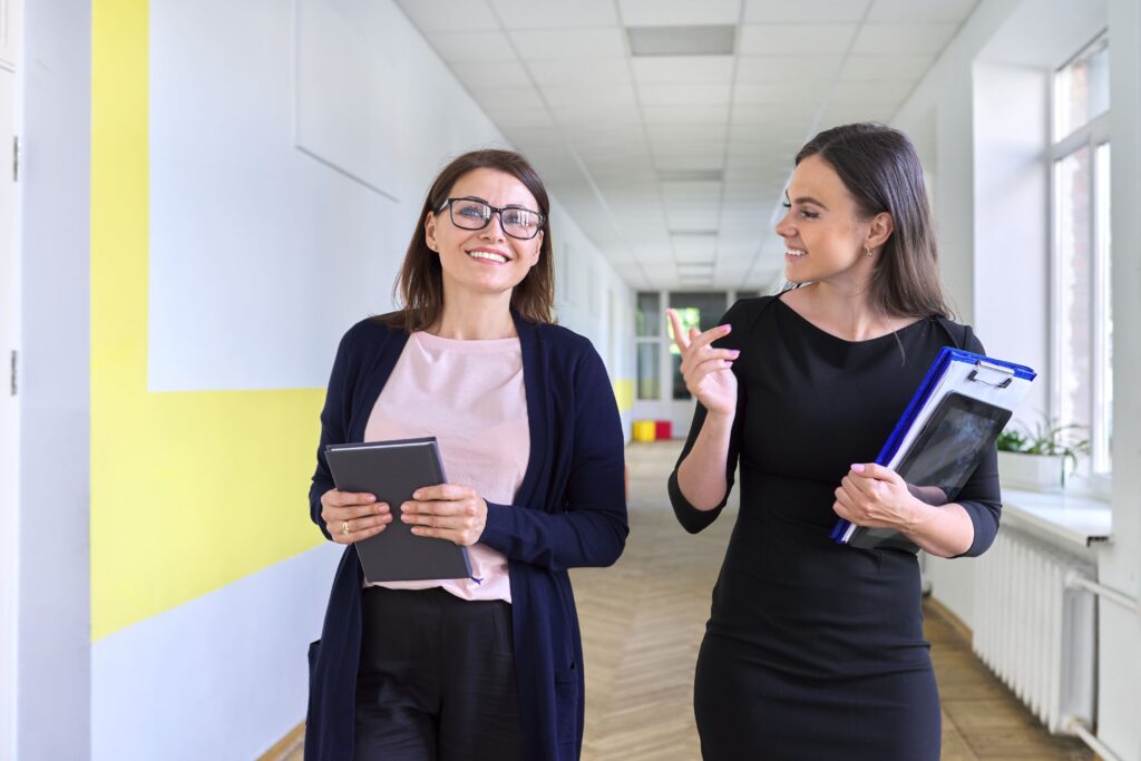 Two female school administrators walking and talking in a corridor