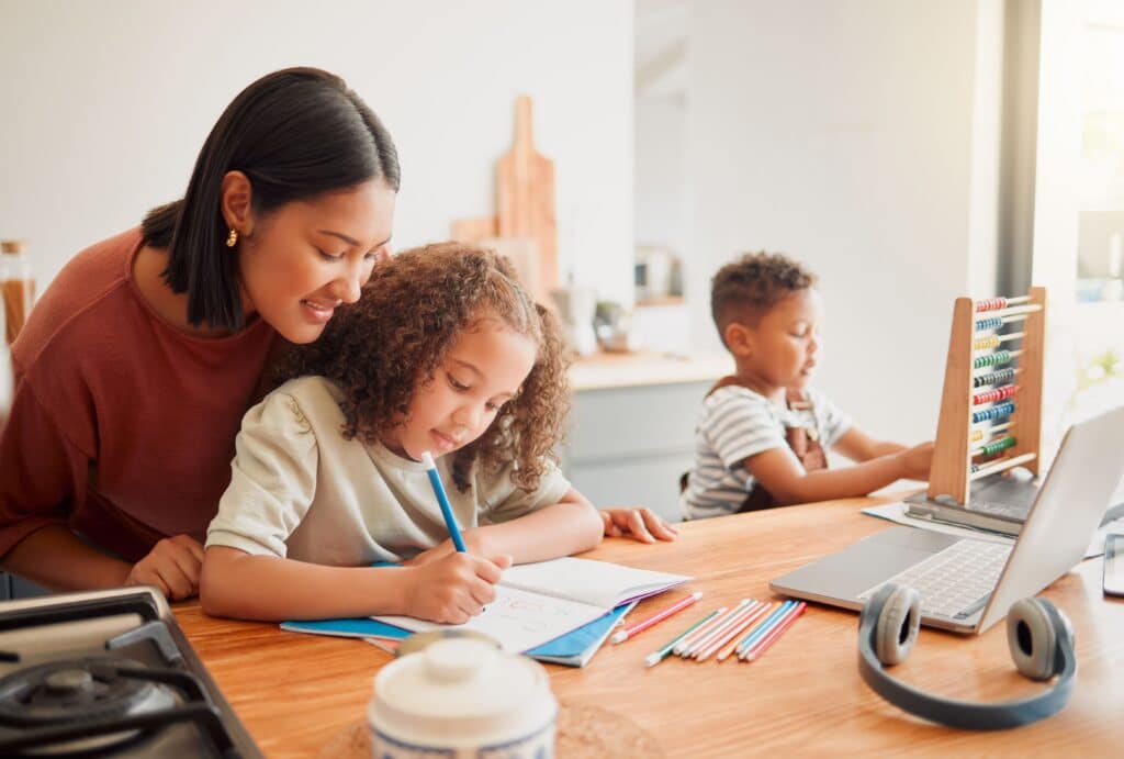 Two young children doing homework with their mother