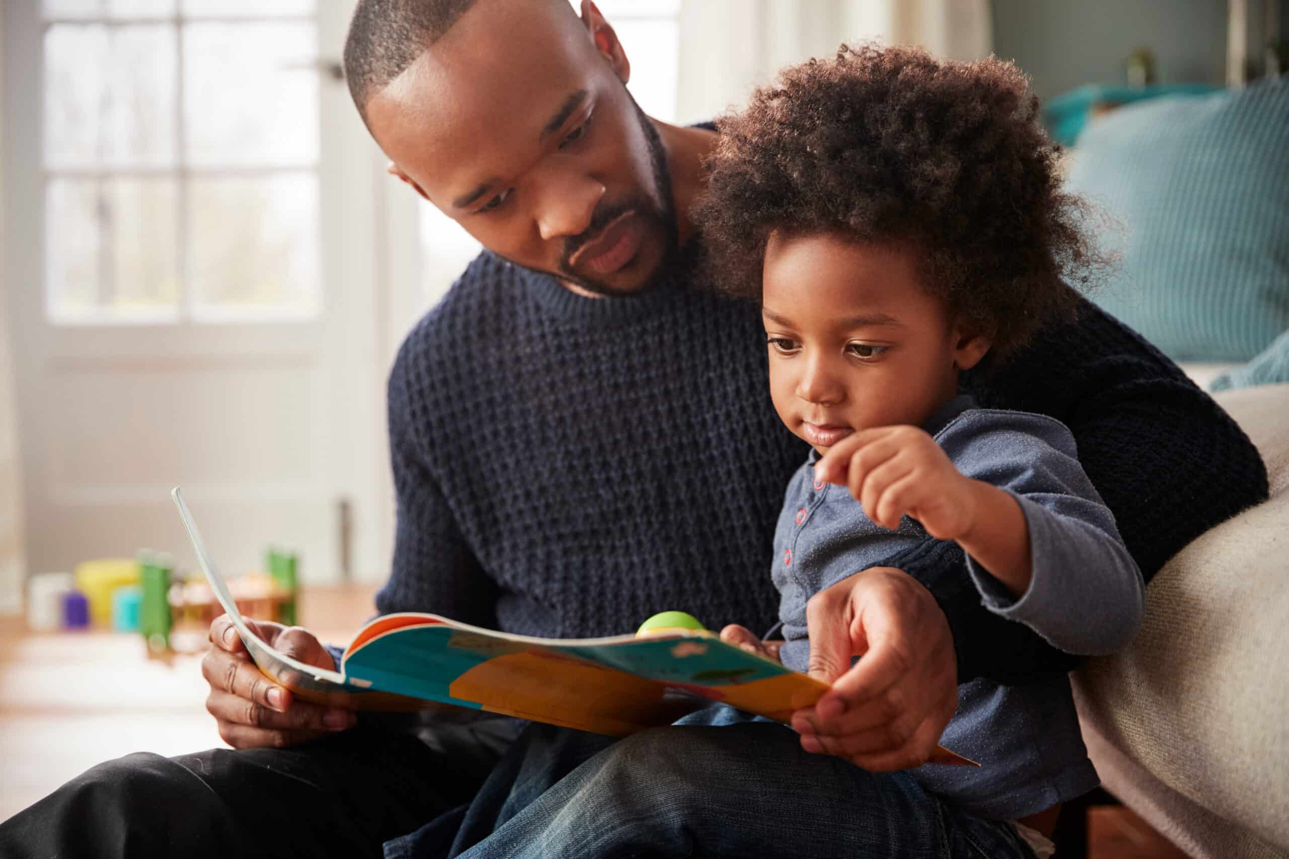 Father and young son reading a book together
