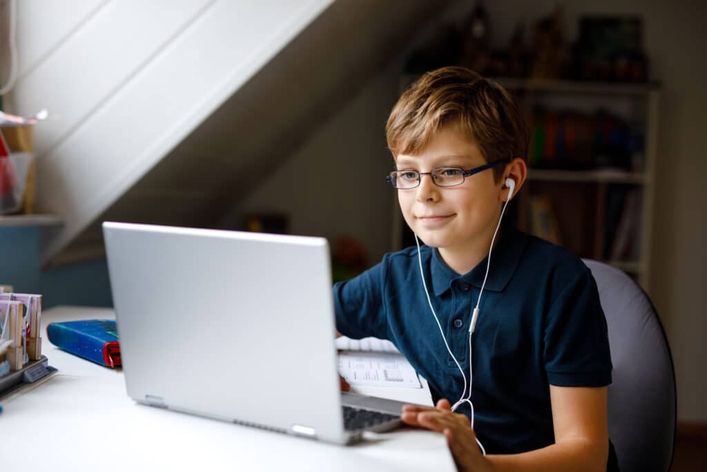 Young boy with glasses and headphones learning to read on a laptop